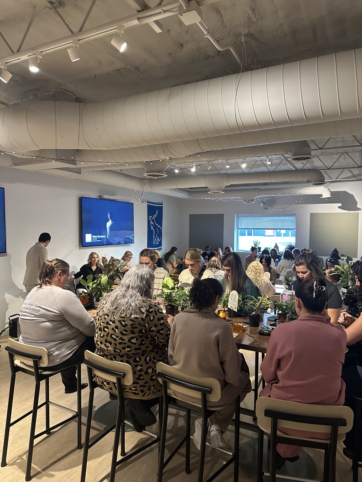 A full room of guests gathered around tables for a social game event
